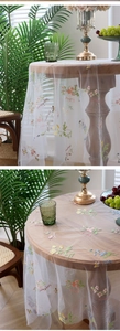 Close-up of colorful floral embroidery and violet text on white sheer lace tablecloth