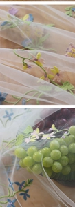Detail of floral embroidery on sheer mesh tablecloth over wood background