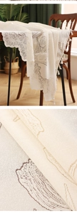 Detailed view of ivory lace tablecloth featuring tulip embroidery and tassel edges