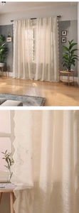 Close-up of cream white lace curtain with delicate tulip floral embroidery and wavy edges