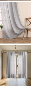 Close-up of light grey tulip lace curtain with delicate floral patterns and scalloped edges
