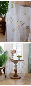 Detailed embroidery of colorful flowers and butterflies on white mesh tablecloth fabric