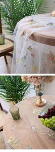 Close-up of floral butterfly embroidery on white semi-transparent mesh tablecloth