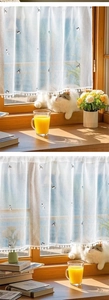 Detail of white semi-sheer cafe curtain with cat embroidery and pom-pom trim on window