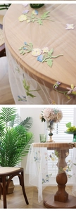 Close-up of floral embroidery on transparent lace tablecloth with colorful butterfly detail