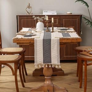 Camino de mesa bohemio beige con rayas y borlas con manteles individuales a juego en madera