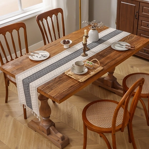 Camino de mesa de lino a rayas con borlas sobre mesa de madera para decoración