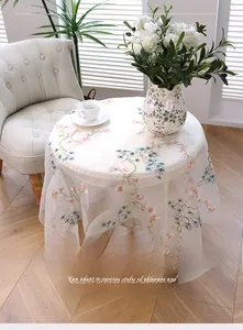 Top view of white sheer mesh tablecloth with pine tree embroidery on a round table