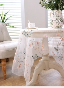 Detail of elegant white mesh tablecloth with pink floral and blue pine needle embroidery