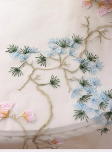 Detailed embroidery of pine branches and pink flowers on mesh tablecloth fabric