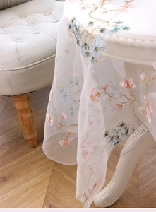 Close-up of elegant sheer mesh tablecloth featuring pine and floral embroidery