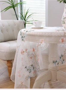 Close-up of floral embroidery on white sheer mesh tablecloth with delicate plant motifs