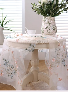 Detail of embroidered pine and floral patterns on elegant white mesh tablecloth