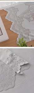 Détail macro du chemin de table en dentelle grise avec broderie florale ajourée raffinée