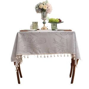 Modern lace tablecloth with tulip jacquard and elegant beige tassel fringe on wooden table