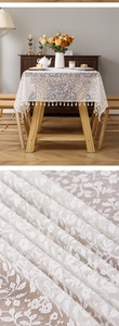 Detail of white French floral lace tablecloth featuring fringe tassels and woven texture