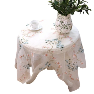 Elegant beige mesh lace tablecloth with floral embroidery on a white vintage table