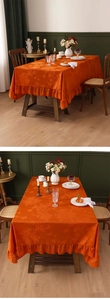 Detail of orange floral jacquard tablecloth with elegant ruffled lace edge and texture
