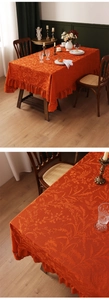 Dettaglio tovaglia rettangolare arancione con trama floreale jacquard e bordi con volant in pizzo