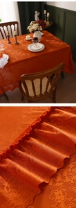 Dettaglio macro di tovaglia in pizzo arancione vintage con bordi a balze e ricami floreali