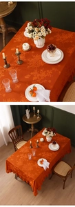 Detail of orange vintage jacquard tablecloth with floral patterns and ruffled edges