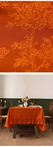 Dettaglio della tovaglia jacquard arancione con rose vintage e bordo in pizzo arricciato