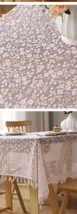 Detailed pink floral lace tablecloth with fringe edge on a rustic wooden dining table