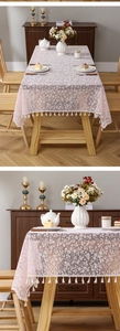 Detail of pink floral lace tablecloth featuring delicate hollow patterns and white tassels
