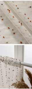 Detail of off-white linen texture cafe curtain with colorful pom-pom balls design
