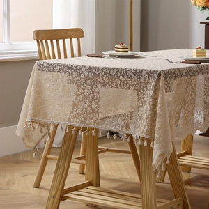 Beige floral lace tablecloth with fringe edge on a wooden table in French retro style