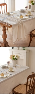 Close-up of geometric embroidery and handmade tassels on beige waterproof table runner