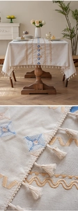 Close-up of geometric diamond embroidery and handmade tassels on beige linen tablecloth