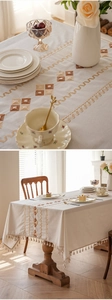 Close-up of geometric embroidery and decorative tassels on a thick beige tablecloth