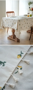 Detail of floral embroidery and cream tassel fringe on waterproof cotton tablecloth