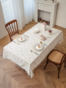 Close-up of pink floral embroidery and white fringe detail on linen tablecloth
