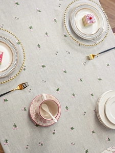 Close-up of pink floral embroidery on linen tablecloth with elegant tea set setting