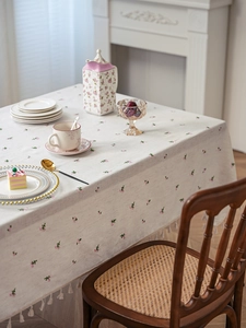 Detail view of linen floral tablecloth with pink flower print and white tassel edges