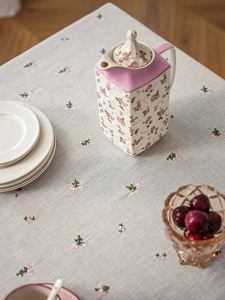 Detailed macro view of gray linen tablecloth with delicate pink floral embroidery detail