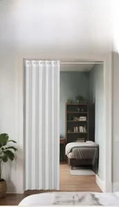Détail d'un rideau pliant blanc installé sur une barre télescopique pour cloisonner