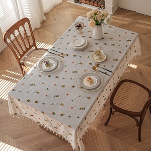 Linen table cloth with octagonal floral embroidery and fringe trim in warm sunlight