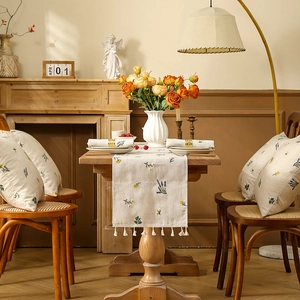 Detailed embroidery of lavender and daisies on linen table runner and matching pillows