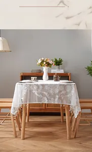 Close-up of white floral lace tablecloth with elegant fringe tassels in a cozy home setting