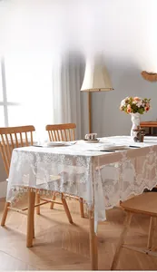 Close-up of white lace tablecloth featuring floral crochet textures and fringe trim