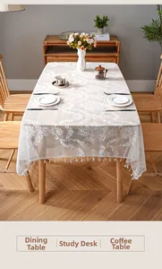 Close-up of white lace tablecloth with floral texture and elegant tassel edge detail