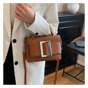 Detail of brown lychee grain leather bag with oversized silver metallic buckle detail