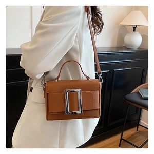 Detailed view of brown litchi pattern bag with a prominent silver metal square buckle detail