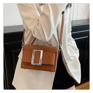 Brown lychee leather crossbody bag featuring a large silver square buckle detail