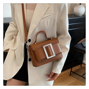 Detail of vintage brown leather bag with large silver buckle on stylish model outfit