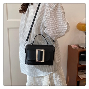 Detail of black lychee texture leather bag featuring a large silver square metal buckle