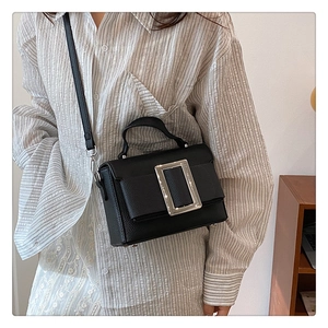 Close-up of black lychee grain leather handbag with iconic silver square buckle detail